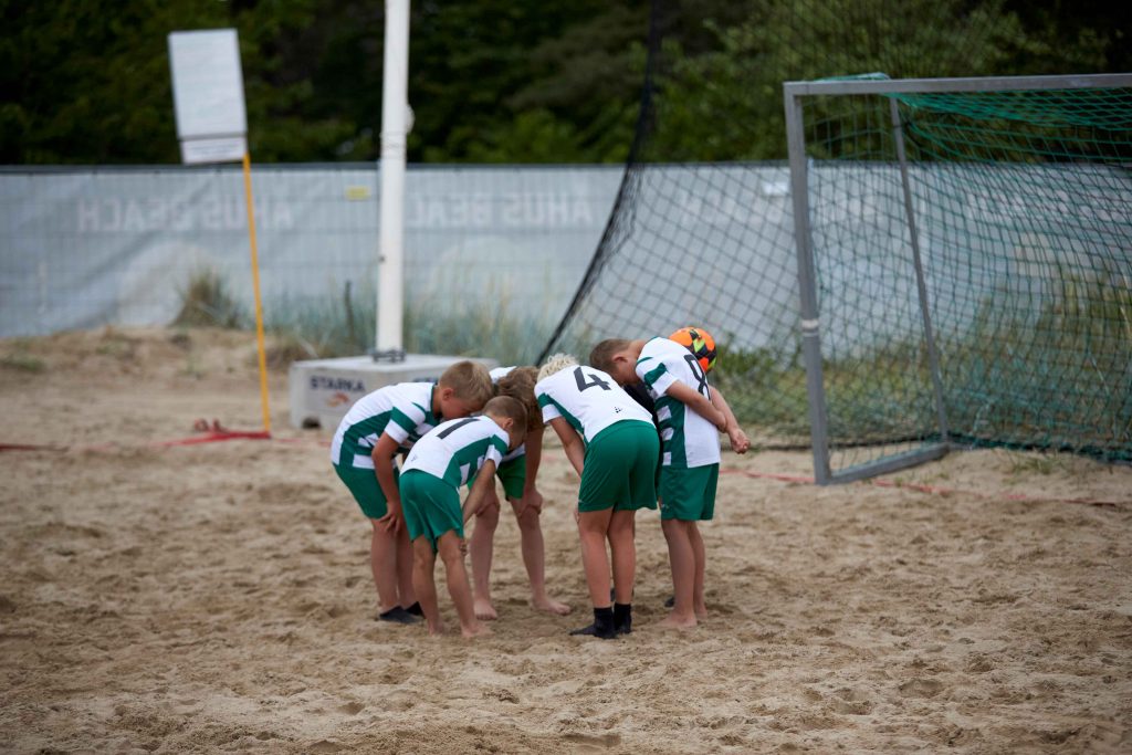 Unga killar pratar tacktik inför beachfotbollsmatch på Åhus Beachfotboll festival