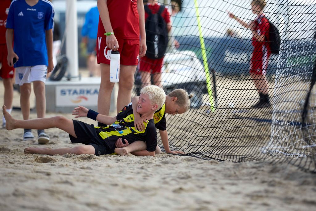 Två pojkar leker på marken på Åhus Beachfotboll festival