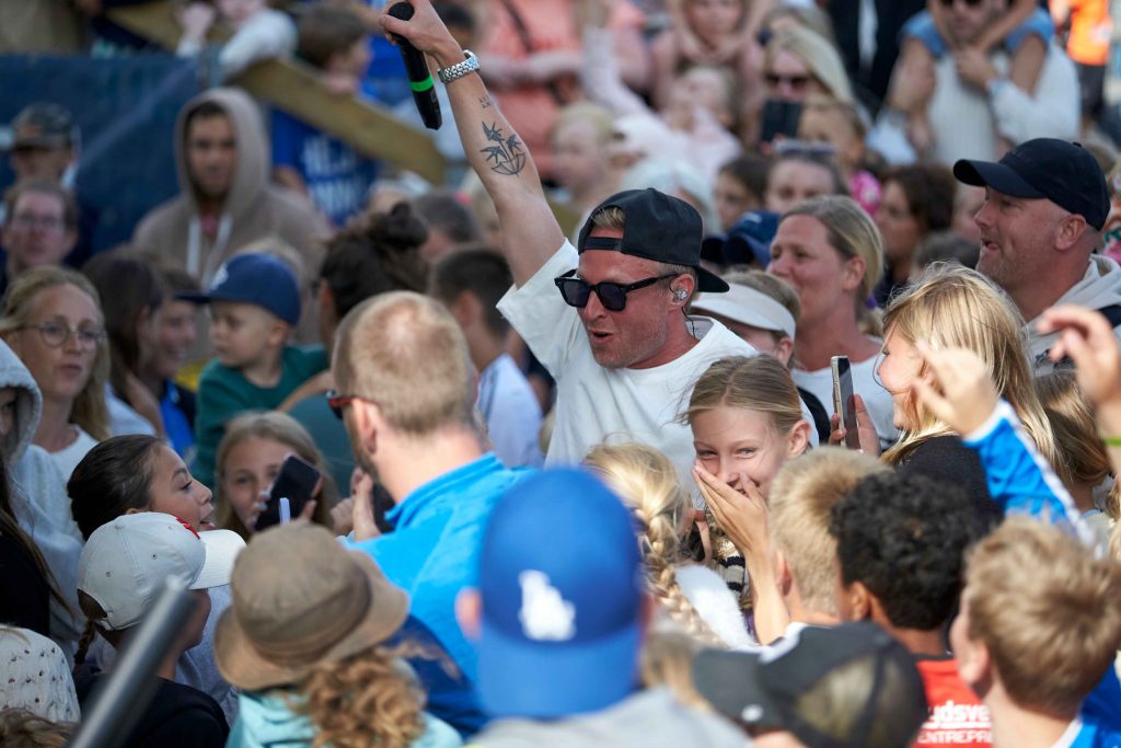 Pidde P uppträder nere i publikhavet som är fyllt av ungdomar på på Åhus Beachfotboll festival