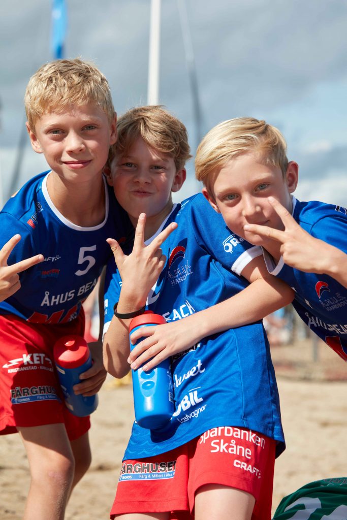 Tre unga killar poserar framför kameran på Åhus Beach Festival.