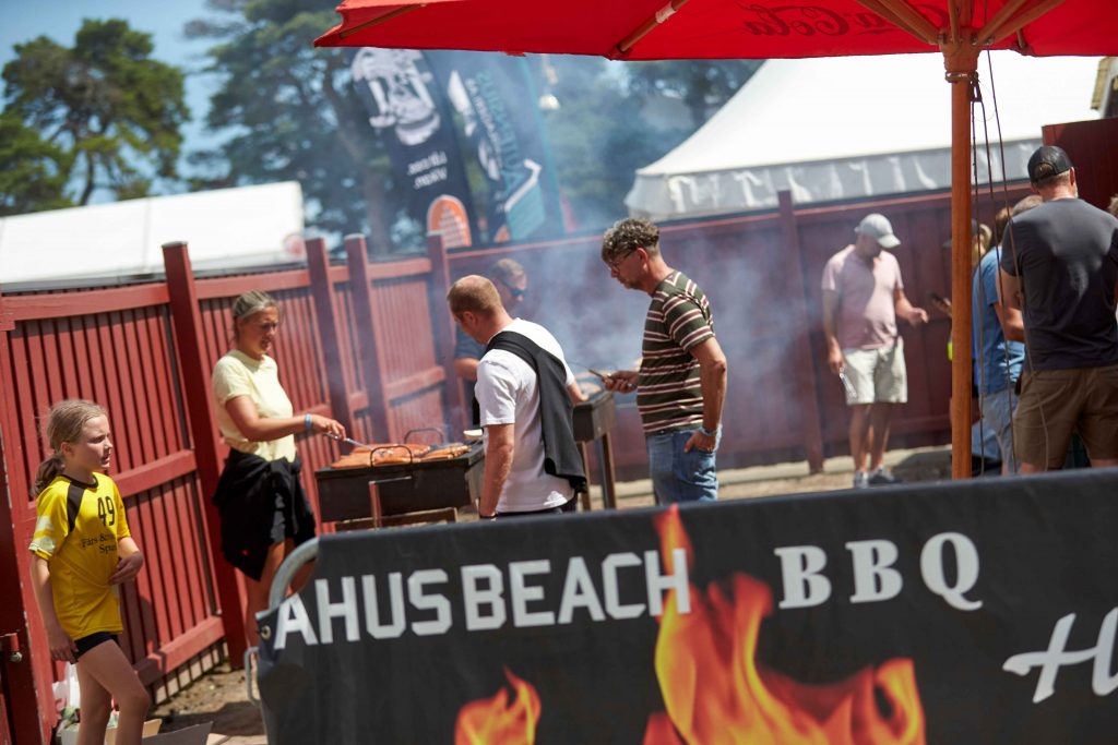 Flera människor Grillar korv i lagtältsbyn på Åhus Beach Festival