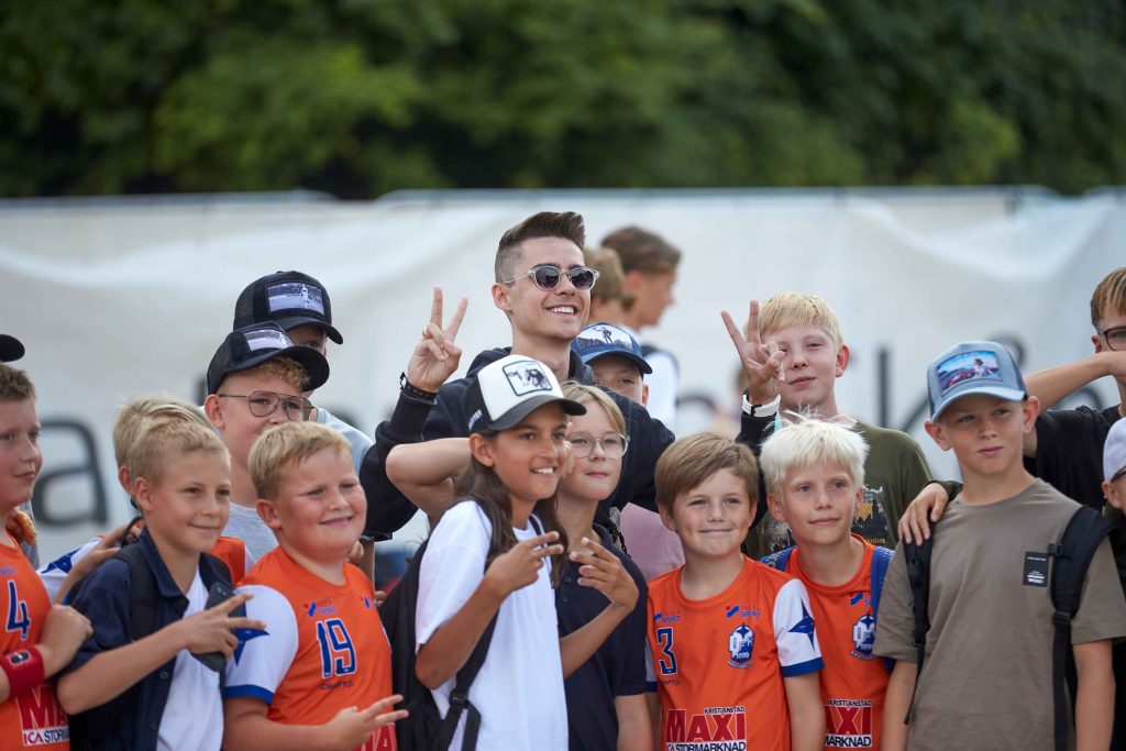 Influensern Olle McDulle inom E sport poserar tillsammans med barn framför kameran på Åhus Beach festival.