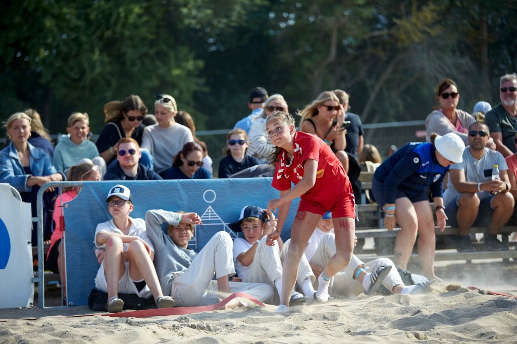 Publik sitter i sanden under match på Åhus Beach festival