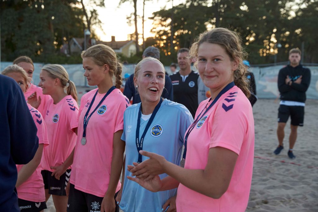 Kvinnligt lag med rosa tröjor tar emot sina silvermedaljer på Åhus Beach Festival