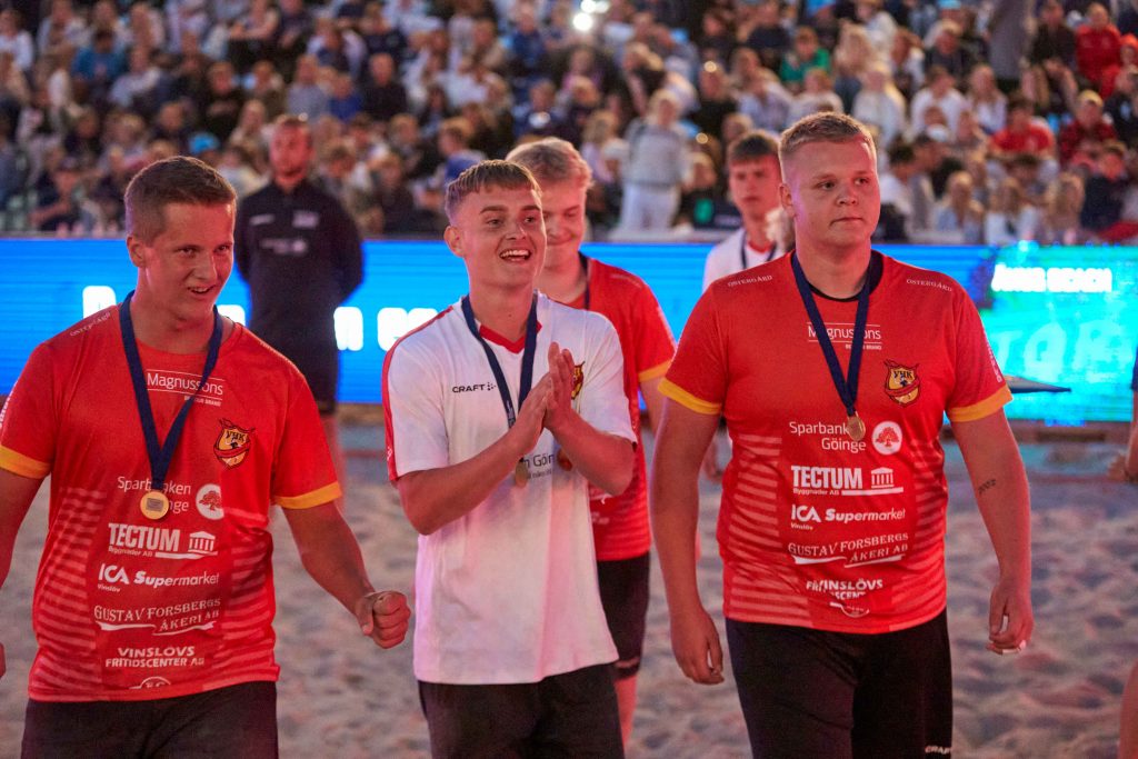 Manligt handbollslag påväg ut från Centercourten med sina guldmedaljer runt halsen på Åhus Beach Festival