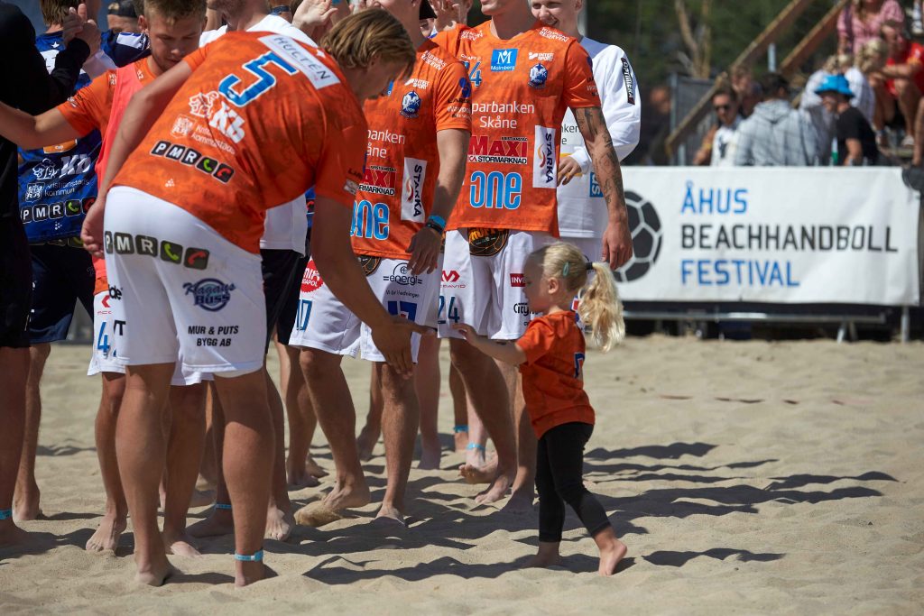 Liten tjej hälsar på IFKspelare på centercourten på Åhus Beach handbolls festival