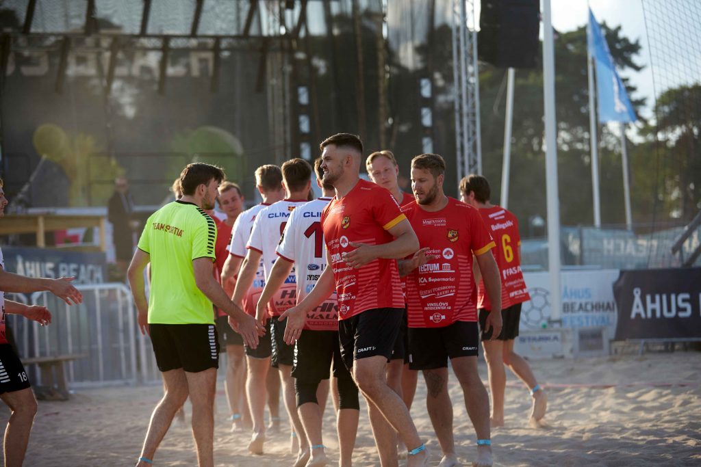 Manliga handbollslag hälsar innan matchen börjar på på Åhus Beach handbolls festival