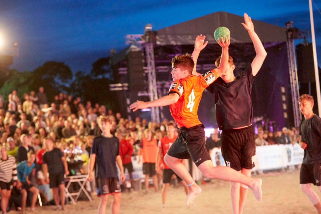Handbollsspelare i luften för att skjuta på mål på Åhus Beach handbolls festival